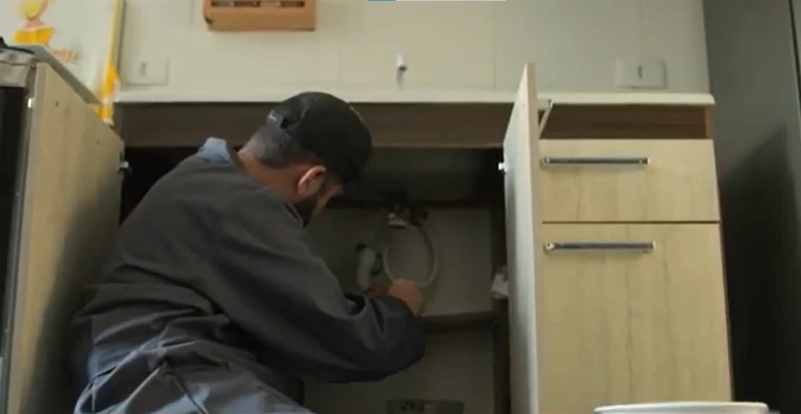 Handyman repairing plumbing under a kitchen sink