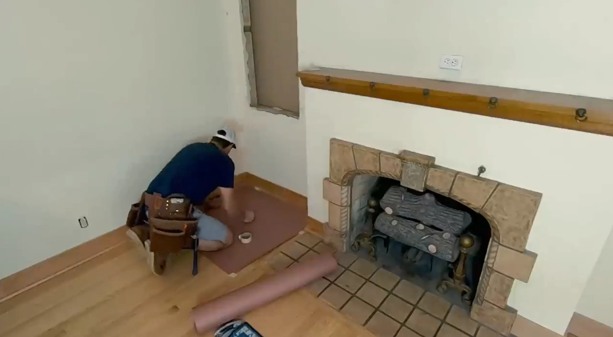 Handyman working on flooring near a fireplace in an older Dayton home